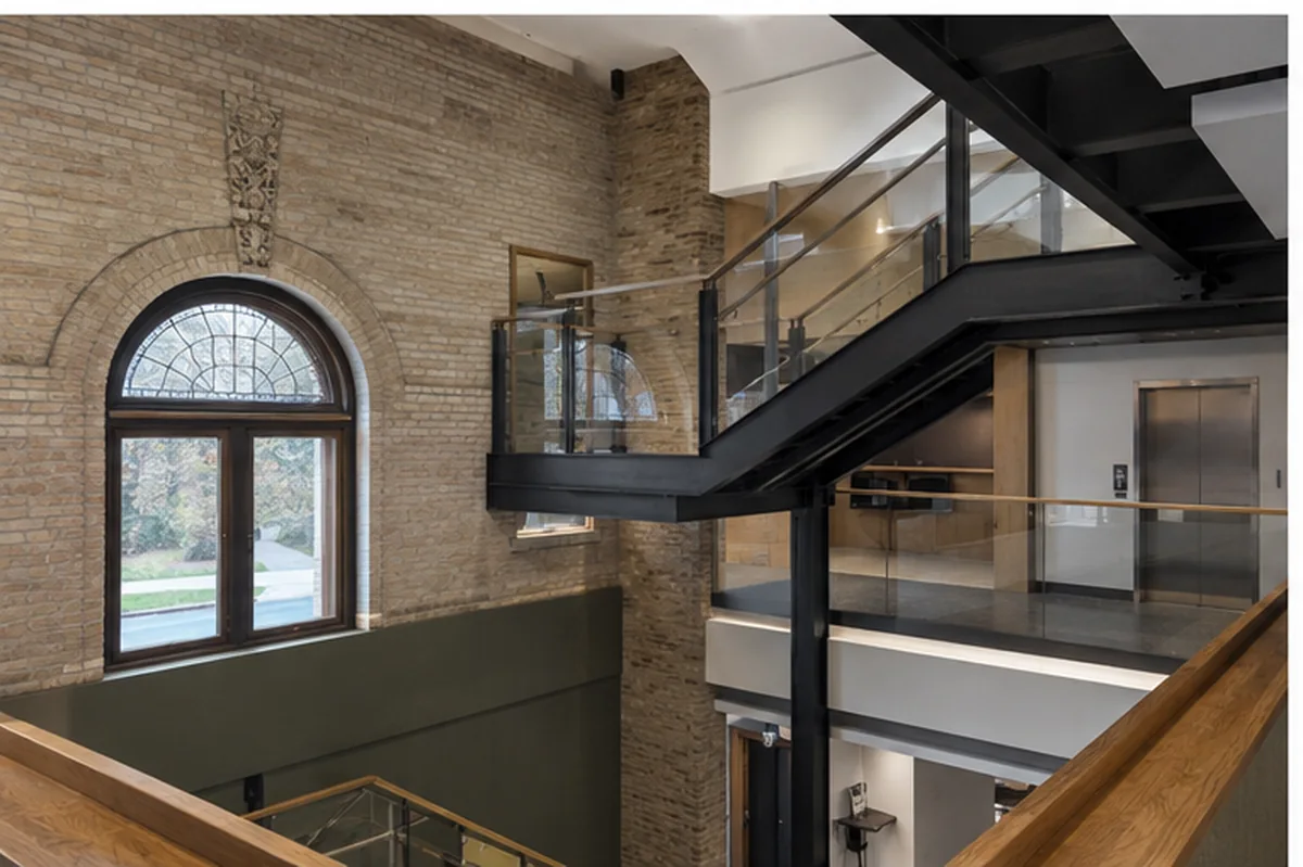 Eastbank Library circulation intervention with new black steel stair inside historic masonry fabric.
