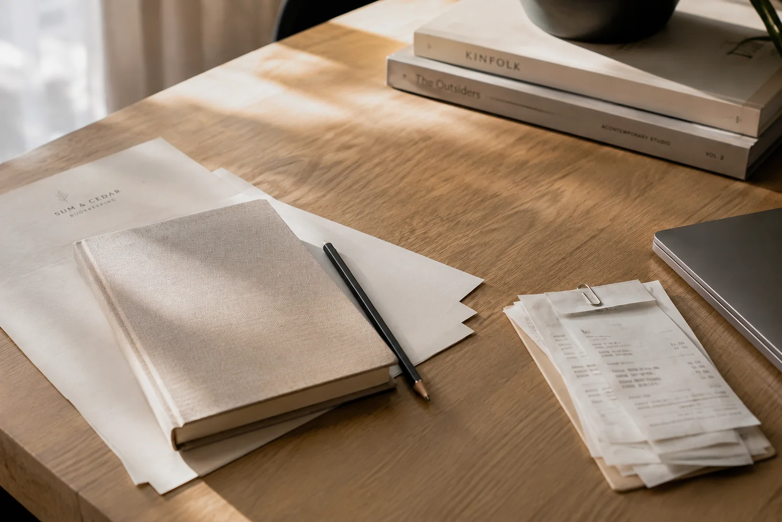 Warm editorial bookkeeping still life with notebook, receipts, paper, and pencil.